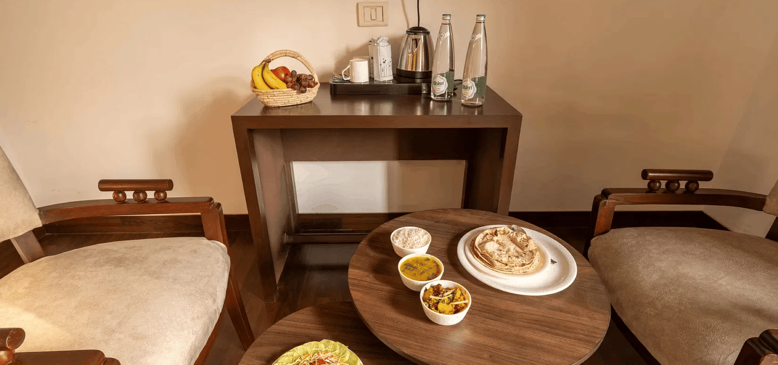 A dining setup with multiple Indian dishes placed on a round table with two chairs - Lime Boutique Bed & Breakfast | Nehru Place Metro